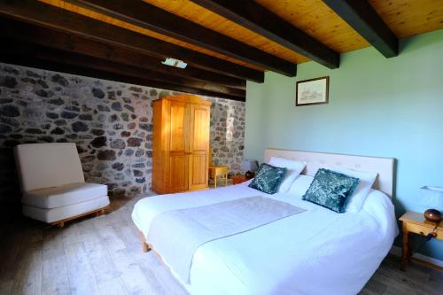 a bedroom with a large white bed and a chair at Ferme de Lamourio in Saint-Cernin