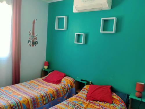two beds in a room with blue walls at L'ABREUVOIR chez l'habitant 1 Chambre d'hôtes lit 140 et 1chambre d'hôtes 2 lits 90 in Surgères