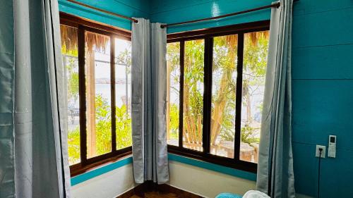 a room with three windows and a blue wall at Mayan Spirit in Flores