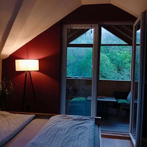 a bedroom with a red wall with a lamp and a window at Funky House Sarajevo in Ilovice