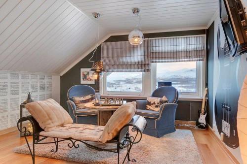 a living room with chairs and a table and windows at RIBO Apartment Katterjåkk in Riksgränsen