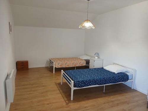 a room with two beds and a table and a lamp at La Grange Landaise in Laglorieuse
