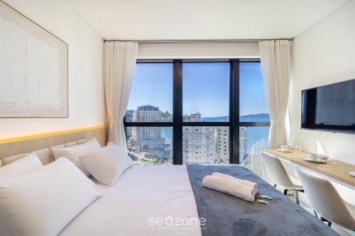 a bedroom with a bed and a desk with a large window at Modern Condominium w/ Sea View Pool, Itapema - MHFB in Itapema