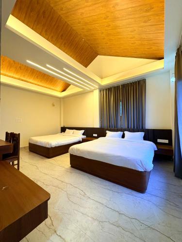a bedroom with two beds and a wooden ceiling at Sittong Aura in Kurseong