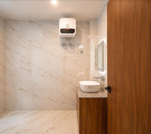 a bathroom with a sink and a soap dispenser on the wall at Sittong Aura in Kurseong