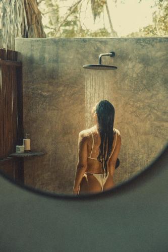 a woman in a bathing suit sitting under a shower at UNÚ Beach Hotel in Palomino