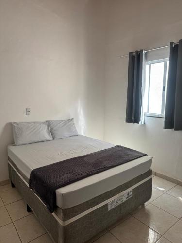 a bed sitting in a room with a window at Palmeira House in Formosa