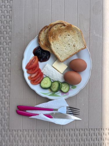 a plate of food with bread eggs cheese and vegetables at Dub Hostel Saranda in Sarandë