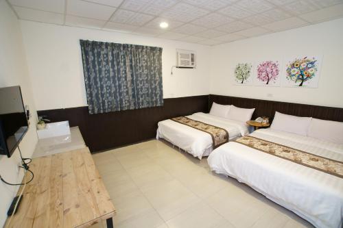 a hotel room with two beds and a television at Fuga Hotel in Taitung City