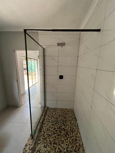 a bathroom with a shower with a tiled wall at Mine Lux Rentals in Thabazimbi