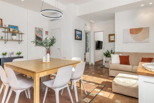 a dining room and living room with a wooden table and white chairs at Grafea - Luxury stay in Catania in Catania