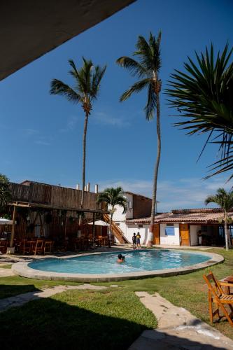a swimming pool with palm trees and people in it at Hotel Luna Nueva in Colán