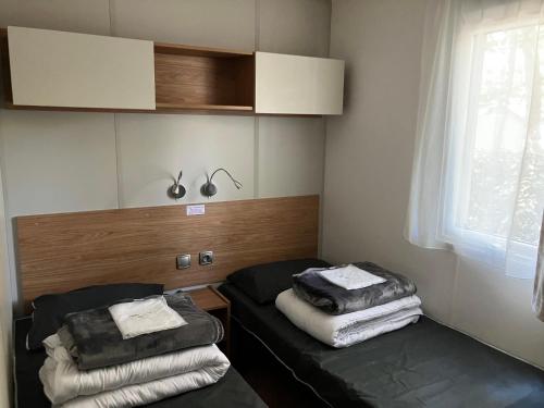a small room with two beds and a window at Grand mobile-home 45M2 au calme et au bord de mer in Saint-Brevin-les-Pins