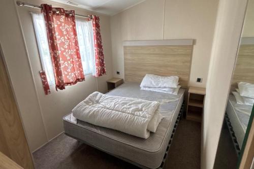 a small bedroom with a bed and a window at Seaside Lodge Haven in St Osyth in Jaywick Sands