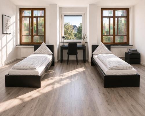 two beds in a room with a desk and windows at Monteurwohnungen in Andervene in Andervenne Oberdorf