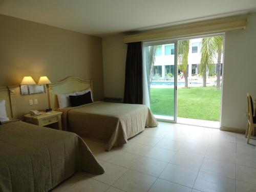 a hotel room with two beds and a large window at Hotel Real de Minas Bajio in León