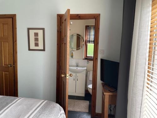 a bedroom with a bed and a bathroom with a television at Old Mills Garden in Elgin