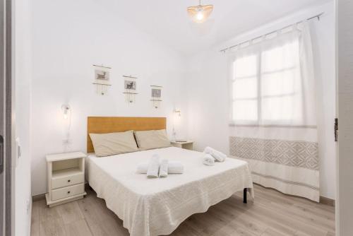 a white bedroom with a bed and a window at Domu Fama in Tertenìa