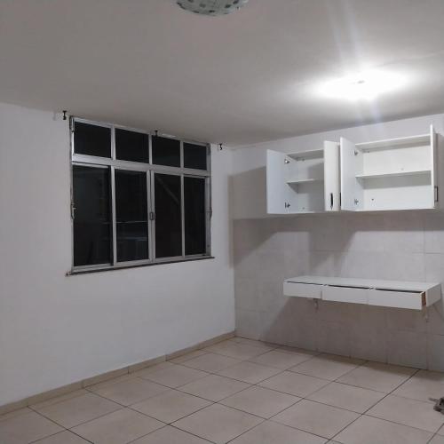 a kitchen with white cabinets and a window at Hostel OS ETERNOS MONIS in Rio de Janeiro