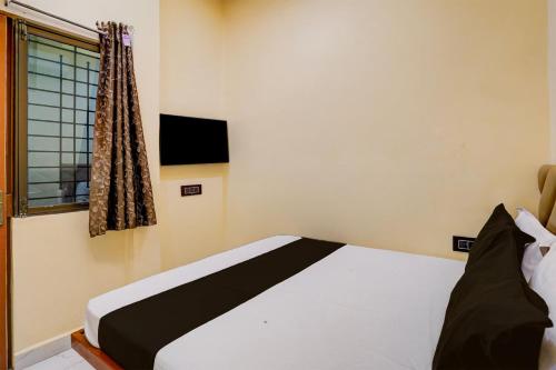 a small bedroom with a bed and a window at Hotel O Utsav In in Jabalpur