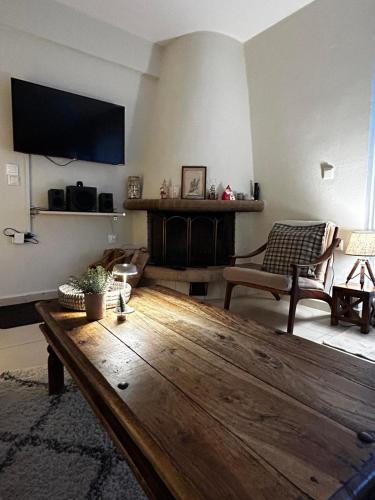 a living room with a wooden table and a tv at Lithos in Khalkoútsion