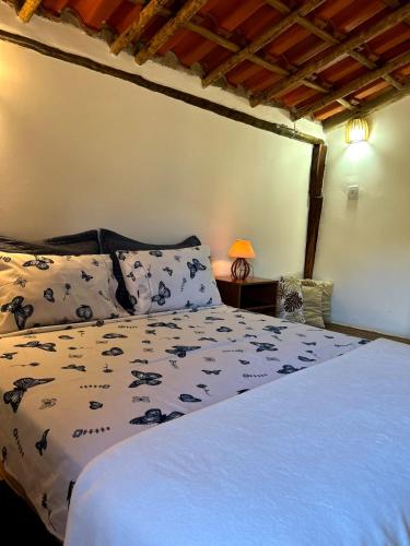 a bedroom with a bed with a white comforter at Chalé Aconchego da Lapinha Vista para Montanhas Piscina e Natureza in Santana do Riacho