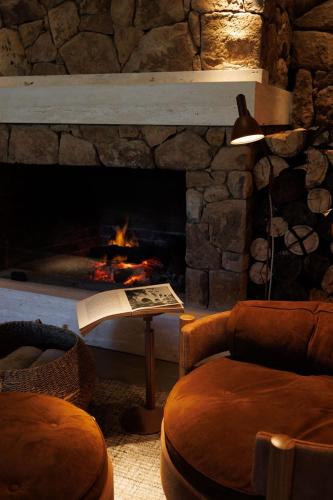 a living room with a fireplace and a chair and a book at Hotel Valle Dincanto in Gramado