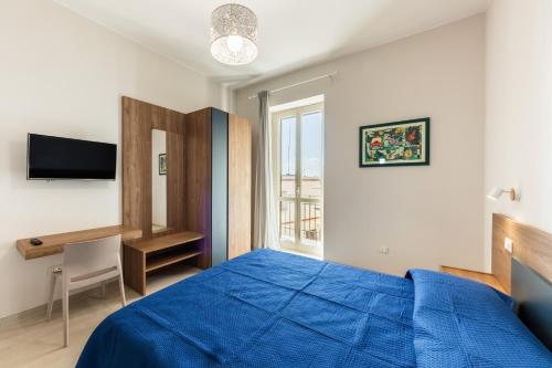 a bedroom with a blue bed and a desk and a window at Casa Amarantia-Appartamento 2 in Noto