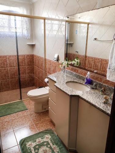 a bathroom with a sink and a toilet and a mirror at Pousada Fernanda in Guarapuava