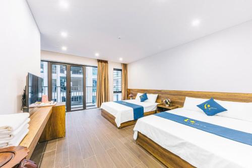 a hotel room with two beds and a balcony at KEY'N'S HOUSE FLC Sầm Sơn in Sầm Sơn