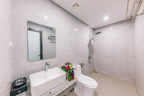 a bathroom with a sink and a toilet and a mirror at KEY'N'S HOUSE FLC Sầm Sơn in Sầm Sơn