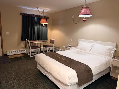 a hotel room with a large bed and a desk at The King's Motel in Sundre