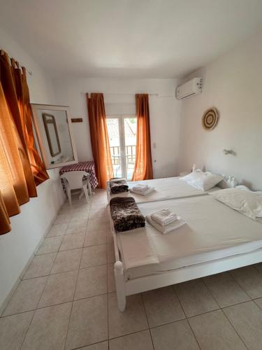 a bedroom with a large white bed with orange curtains at Joanna Rooms in Skala Eresou