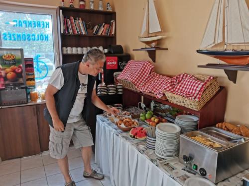a man standing in front of a table with food at Nautica Stúdió by HelloBalatonlelle in Balatonlelle
