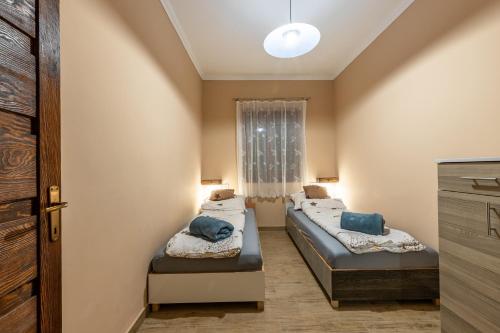 two beds in a small room with a window at Hege Vendégház in Bükkmogyorósd