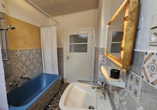 a bathroom with a blue tub and a sink at Helle Ferienwohnung - Südeifel bei Neuerburg in Ammeldingen