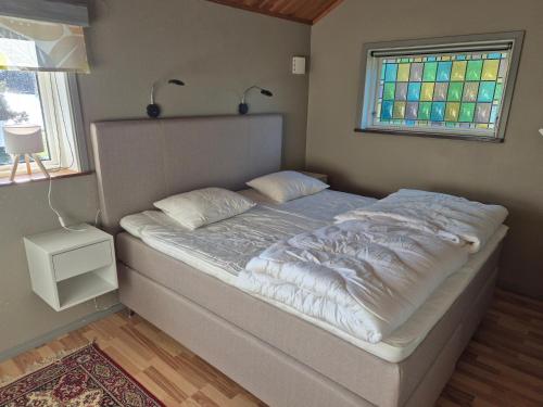 a bed in a bedroom with a stained glass window at Åker Lilläng Solviken in Skillingaryd