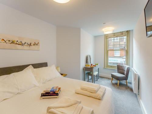 a white bedroom with a bed and a chair at 2 Bed in Brockenhurst oc-78729 in Brockenhurst