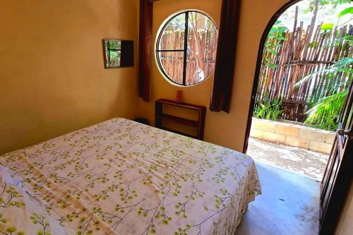 a bedroom with a bed and a large window at Hostal Mulut Tulum in Tulum