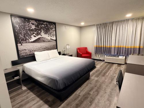 a hotel room with a bed and a red chair at Super 8 by Wyndham Macomb in Macomb