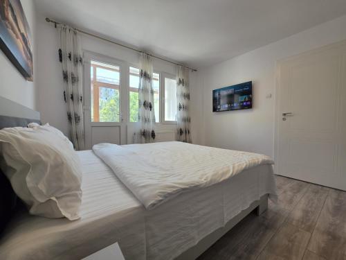 a white bedroom with a large bed and a window at Konstanzer Podu Ros 11 - Spacious Apt - Palas Mall - AC in Iaşi