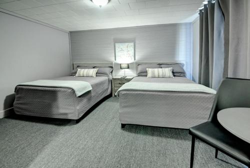 a bedroom with two beds and a table and a chair at Motel Express in Saint-Antonin