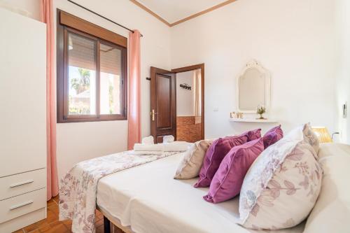 a white bedroom with a bed with purple pillows at Casa Rural Villa Lucrecia in La Lantejuela