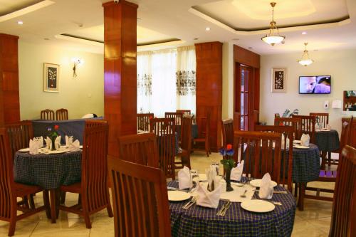 uma sala de jantar com mesas e cadeiras num restaurante em Grace Land Hotel em Arusha