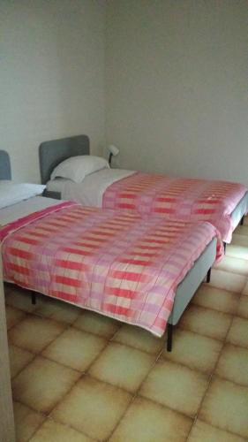 two beds in a bedroom with a red and white blanket at B&B Porta Roma in Capua