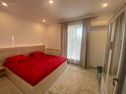 a bedroom with a red bed and a window at Apartament Kiri in Mangalia