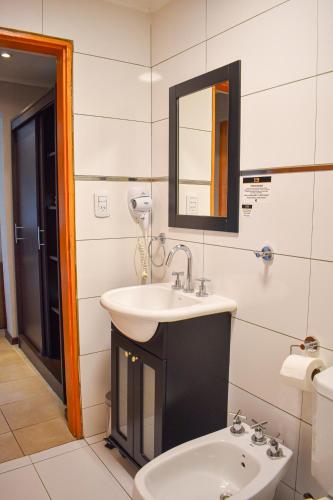a bathroom with a sink and a mirror and a toilet at Demetrio Hotel Apart in Olavarría