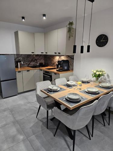 a kitchen with a wooden table and chairs and a kitchen with white cabinets at Blue Wave Pobierowo in Pobierowo