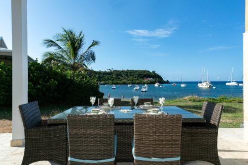 a dining table and chairs with a view of the water at Mahalo Villa Beachfront Generator in Cruz Bay