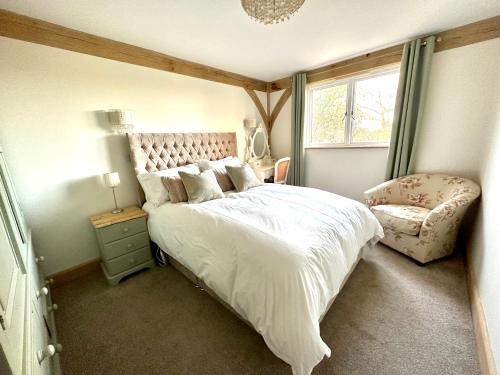 a bedroom with a large bed and a chair at Holly Barn in Worcester